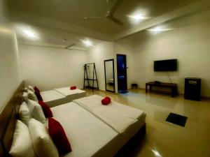 a bedroom with two beds with red pillows and a television at Ocean Light Mirissa in Mirissa