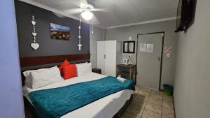 a bedroom with a bed with a blue blanket at Honey Bee Guesthouse in Rustenburg +26 photos