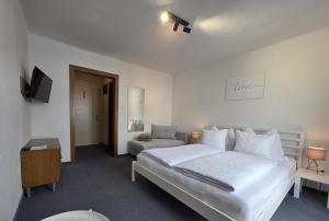 a white bedroom with a bed and a couch at Frühstückspension Irschen in Irschen