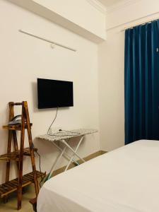 Vantage View - 2BHK Apartment في Nalmatha: غرفة نوم بها سرير ومكتب عليه تلفزيون