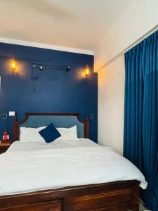Vantage View - 2BHK Apartment في Nalmatha: غرفة نوم بها سرير وجدار أزرق