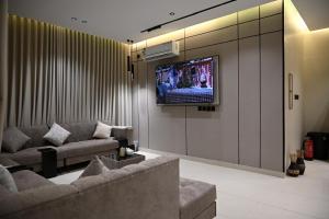 a living room with a couch and a tv on a wall at شاليه لانتانا in Taif