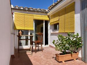 a patio with yellow blinds and a chair on a balcony at Casa Taller en Penelles in Penellas