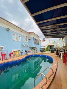 a swimming pool with red chairs and a blue house at Garden Atlantis Hotel in Enugu