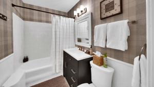 a bathroom with a sink and a toilet and a tub at In-ground pool, hot tub, fire pit, massage room! in Tulsa +46 photos