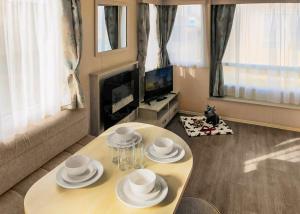 a living room with a table and a tv at Towervans Caravan Park in Mablethorpe