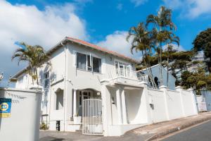a white house with a white fence and palm trees at Pearlstone in Durban