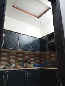 a kitchen with black cabinets and a white ceiling at Suites Inn in Faisalabad
