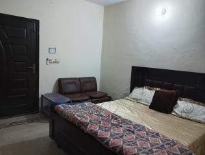 a bedroom with a bed and a chair in it at Suites Inn in Faisalabad