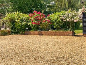 a garden with pink flowers and a brick wall at Rumbolds Retreat in Plaistow