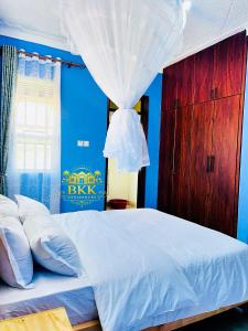 a bedroom with a white bed with a blue wall at BKK Residences in Fort Portal