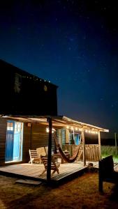 a deck with a hammock and chairs at night at Casa Satori in Barra de Valizas