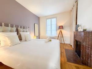 a bedroom with a large white bed and a fireplace at Les Volets Bleus in Chartres