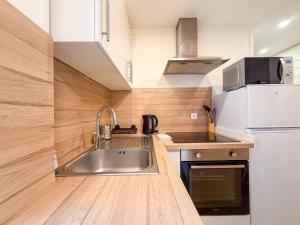 a kitchen with a sink and a white refrigerator at Les Volets Bleus in Chartres