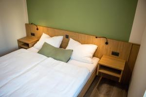 a bedroom with a white bed with a green wall at Bärenhof in Matzen