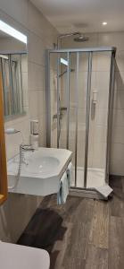 a white bathroom with a shower and a sink at Hotel Walkenstein in Oberwolfach
