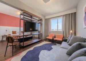 a living room with a couch and a table with a tv at Intercity Porto Alegre Cidade Baixa in Porto Alegre