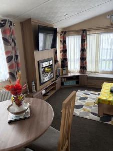 a living room with a table and a television at Sleeps 8 guests lovely 3 Bedroom Golden Gate Towyn in Llanddulas