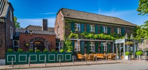 a building with tables and chairs in front of it at Wellings Romantik Hotel zur Linde in Moers