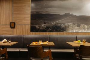 a restaurant with two tables and a picture of a mountain at Leonardo Hotel Eindhoven City Center in Eindhoven +34 photos