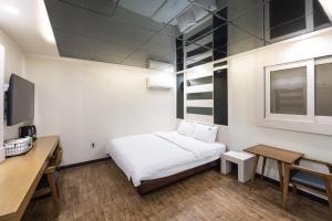 a small room with a bed and a desk and a table at Lien Hotel Haeundae in Busan