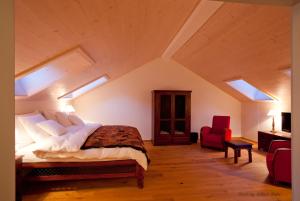 a bedroom with a large bed and a red chair at Le Jardin de Kabir in Martigny-Ville
