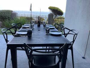 a wooden table with chairs and plates and wine glasses at The Tarp at Whale Cove in De Kelders