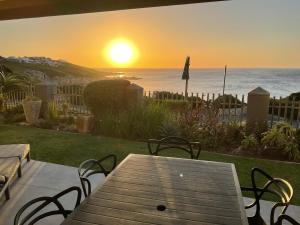 a picnic table with a view of the ocean at sunset at The Tarp at Whale Cove in De Kelders