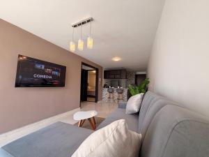 a living room with a couch and a tv at Espacio cómodo, piscina, jacuzzi y parqueadero in San Gil
