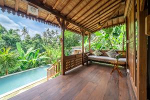 a porch of a house with a bench and a pool at Saughina Ubud in Ubud