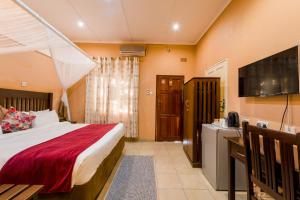 a hotel room with a bed and a television at Victoria Falls Premier Lodge in Victoria Falls