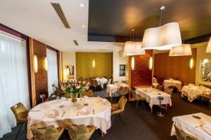 a dining room with white tables and chairs and flowers at Logis Hotel Le Parc in Moulins