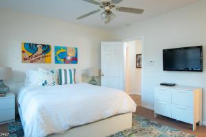a bedroom with a white bed and a flat screen tv at Maison du Soleil in Palm Springs