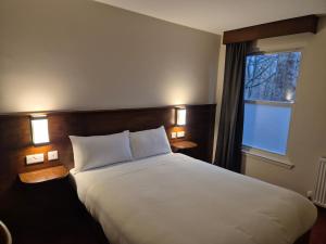 a bedroom with a large white bed and a window at Woodside House in Aberdeen