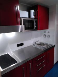 a kitchen with red cabinets and a sink and a microwave at Refugium.311 in Bad Reichenhall