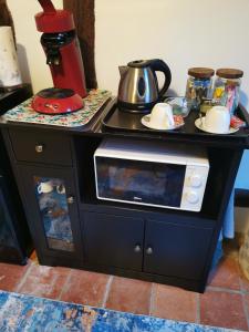 a black cabinet with a microwave on top of it at Le Petit Verger in Grumesnil