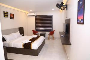 a bedroom with a bed and a desk and a television at Elara Residency Cheravathur in Cheruvattūr +9 photos