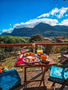 a table with food and drinks on a balcony with mountains at Chalé com Jacuzzi vista para Pico da Lapinha in Santana do Riacho