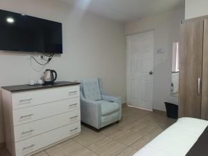 a bedroom with a dresser with a tv and a chair at Hotel Cortaderas Arequipa in Yanahuara