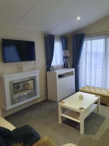a living room with a fireplace and a flat screen tv at Jasper Lodge in Morecambe