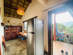 a kitchen with a stainless steel refrigerator and a table at Chalé com Jacuzzi vista para Pico da Lapinha in Santana do Riacho