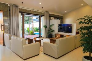 a living room with white furniture and a flat screen tv at Le Casa Villa by hotel travel inn in Pokhara