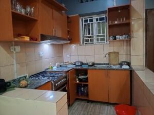 a kitchen with wooden cabinets and a stove top oven at Akagera Sunset House in Kabarondo