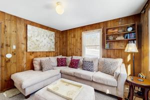 a living room with a white couch and wooden walls at Sugarbush River Home in Warren