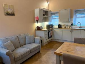 a living room with a couch and a kitchen at The Cow 'ouse, Wolds Way Holiday Cottages, 1 bed cottage in Little Weighton