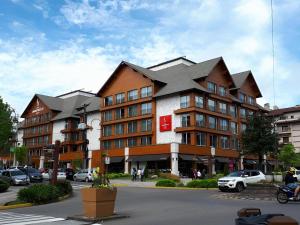 a large building in a parking lot with cars parked at Laghetto Stilo Borges - Apto 403B in Gramado