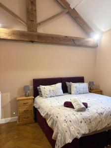 a bedroom with a large bed with wooden ceilings at The Cow 'ouse, Wolds Way Holiday Cottages, 1 bed cottage in Little Weighton