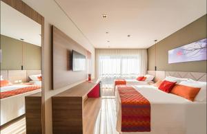 a hotel room with two beds and a tv at Laghetto Stilo Borges - Apto 403B in Gramado
