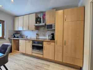 a kitchen with wooden cabinets and a microwave at 84m2 Ferienwohnung - Landquartier Moik Ankommen - Durchatmen - Abschalten in Ebenthal