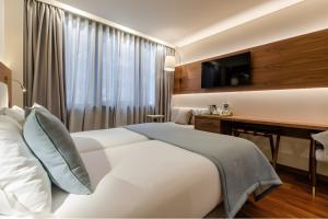 a hotel room with a bed and a desk and a television at TURIM Av. Liberdade Hotel in Lisbon